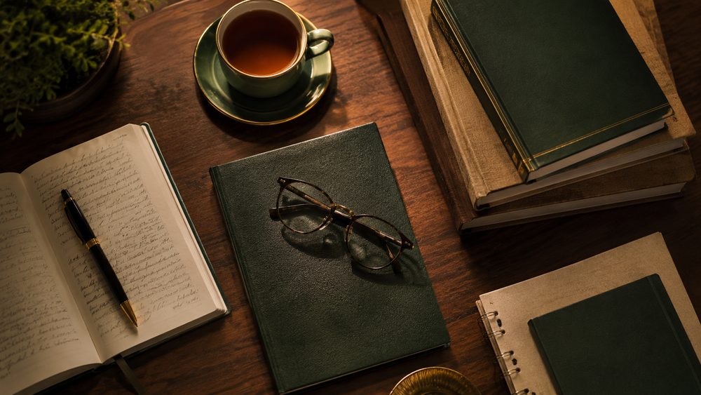 Course study materials — books, notebook, reading glasses and tea on a wooden desk